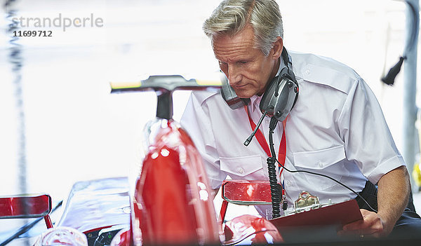 Manager mit Zwischenablage neben Formel 1 Rennwagen