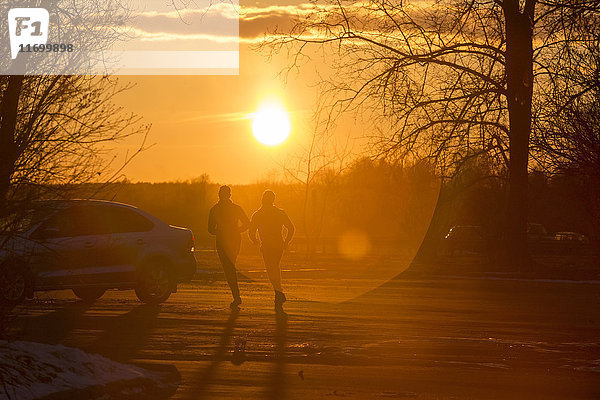 Silhouette von zwei Joggern im Winter bei Sonnenuntergang