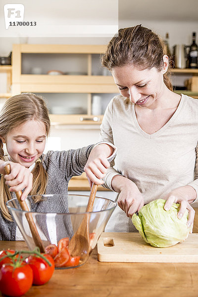 Mutter und Tochter kochen Salat in der Küche
