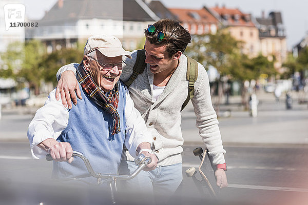 Glücklicher älterer Mann mit erwachsenem Enkel in der Stadt unterwegs
