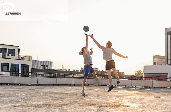 Freunde beim Basketball bei Sonnenuntergang auf einem Dach