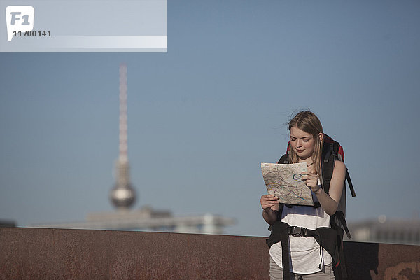 Deutschland  Berlin  Junge Frau mit Rucksack auf der Landkarte