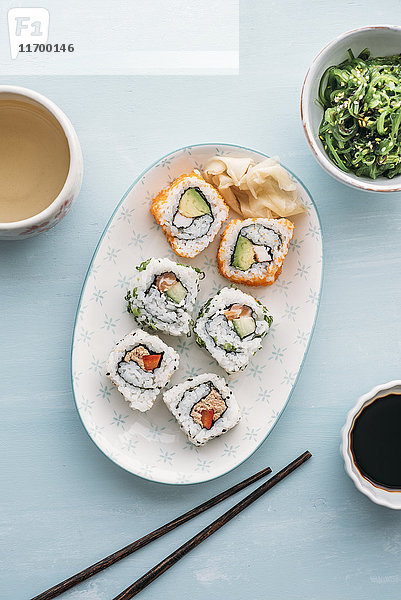 Sushi-Rollen auf einem Teller  Wakame-Algensalat und Grüntee