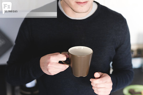 Mann mit Tasse Kaffee in der Küche  Teilansicht