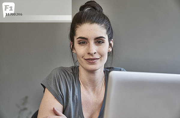 Porträt einer lächelnden jungen Frau mit Laptop