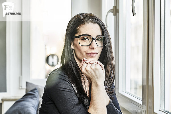 Bildnis einer jungen Frau mit Brille am Fenster