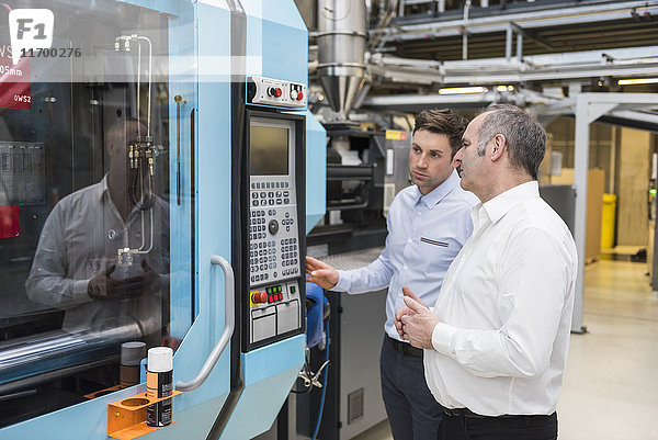 Zwei Männer betrachten die Maschine in der Fabrikhalle