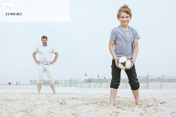 Porträt eines lächelnden kleinen Jungen  der mit seinem Vater am Strand spielt.