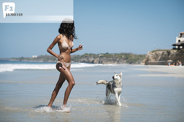 Mexiko  Riviera Nayarit Strand  junge Frau läuft mit Husky-Hund