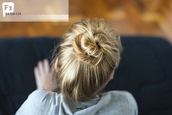 Frau mit Ingwerhaarbrötchen auf dem Sofa sitzend