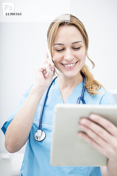 Lächelnder Arzt am Telefon mit Blick auf die Tablette