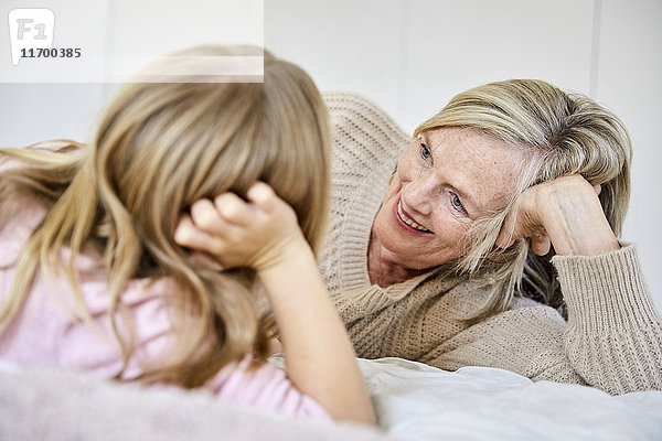 Seniorin entspannt mit ihrer Enkelin auf dem Bett