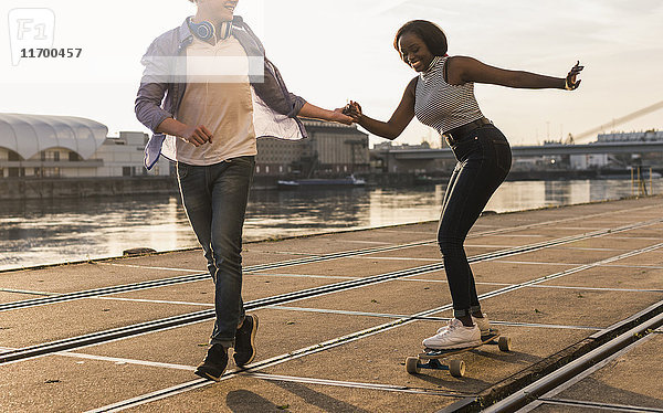 Junges Paar beim Skateboarden am Flussufer