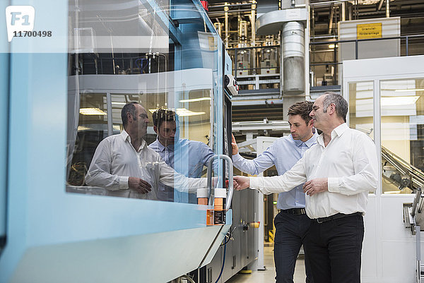 Zwei Männer betrachten die Maschine in der Fabrikhalle