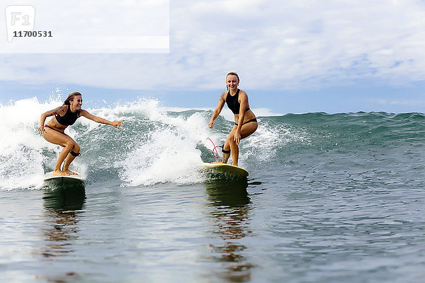 Zwei Mädchen beim Surfen im Meer