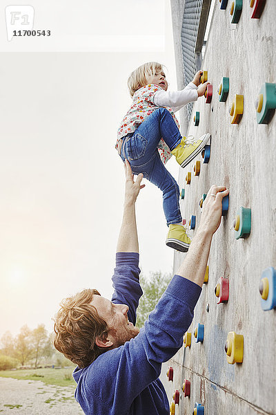 Mädchen klettert auf eine von Vater getragene Wand