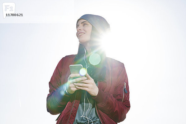Lächelnde junge Frau mit Handy im Freien