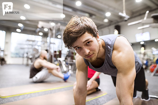 Porträt eines jungen Mannes  der im Fitnessstudio trainiert.