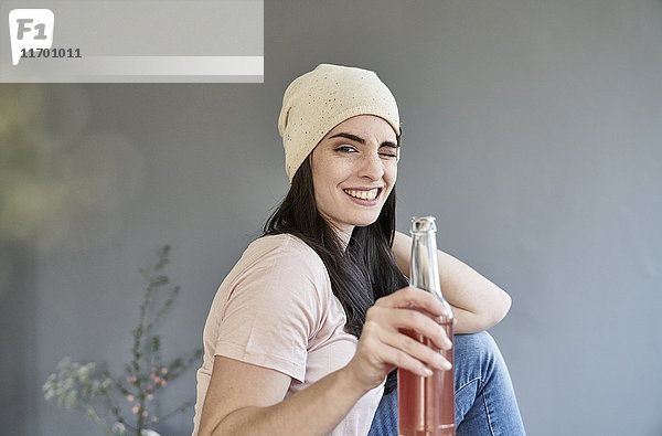 Porträt einer lächelnden jungen Frau mit funkelnder Halteflasche