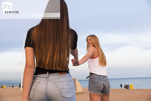 Zwei glückliche junge Frauen Hand in Hand am Strand
