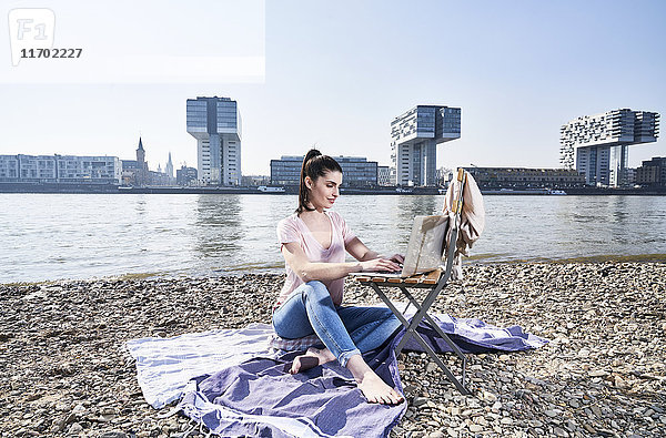 Deutschland  Köln  junge Frau mit Laptop am Rhein
