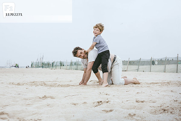 Vater und kleiner Sohn spielen zusammen am Strand.