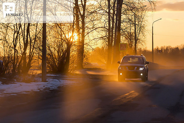 Auto auf der Straße im Winter bei Sonnenuntergang