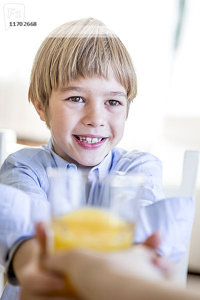 Lächelnder Junge mit einem Glas Orangensaft