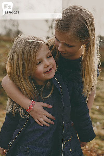 Mädchen umarmt ihre Schwester im Freien