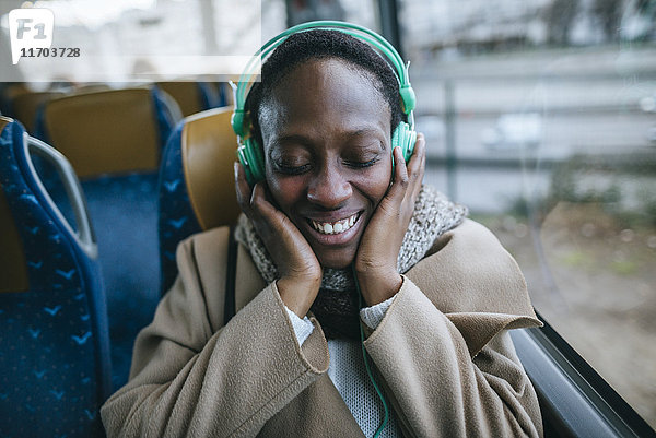 Fröhliche junge Frau beim Musikhören im Bus