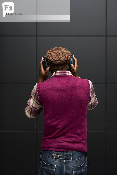 Rückansicht des Mannes beim Musikhören mit Kopfhörer und Handy