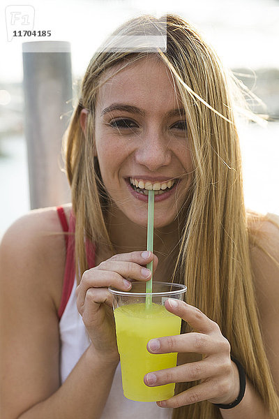 Lachende junge Frau mit gelbem Getränk