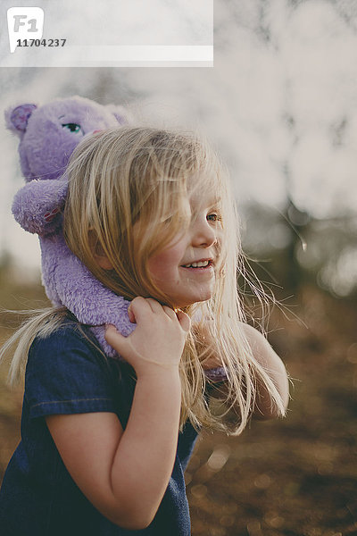 Lächelndes Mädchen mit einem Teddy im Freien