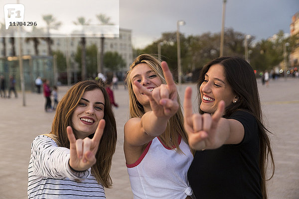 Spanien  Barcelona  drei glückliche junge Frauen mit Rock And Roll Sign