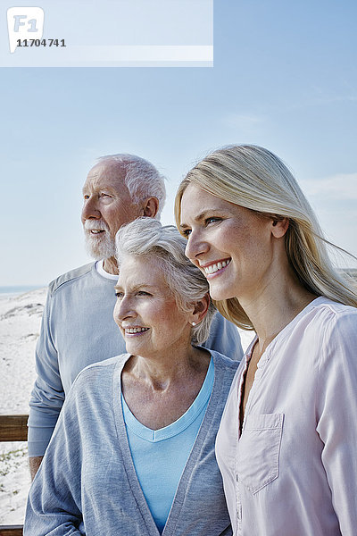 Lächelndes Seniorenpaar mit erwachsener Tochter am Strand
