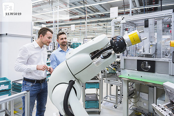 Zwei Männer betrachten den Montageroboter in der Fabrikhalle