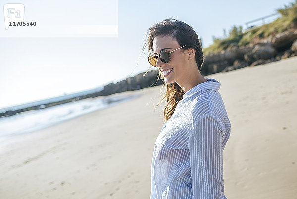 Lächelnde junge Frau mit Sonnenbrille am Strand