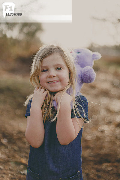 Lächelndes Mädchen mit einem Teddy im Freien