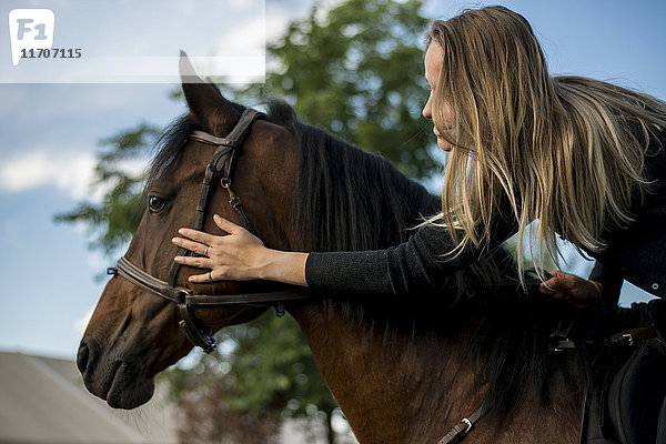 Junge Frau reitend streichelndes Pferd