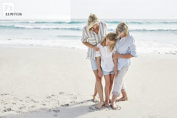 Mutter  Tochter und Großmutter in einem Herzen stehend  in den Sand am Strand gezogen