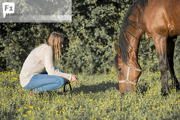 Junge Frau mit Pferd auf der Wiese