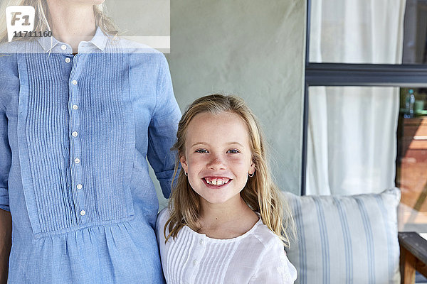 Porträt des lächelnden Mädchens neben ihrer Mutter auf der Terrasse