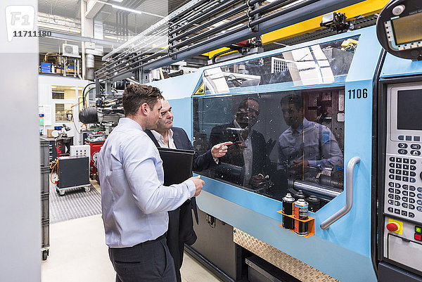 Zwei Männer reden über Maschinen in der Fabrikhalle