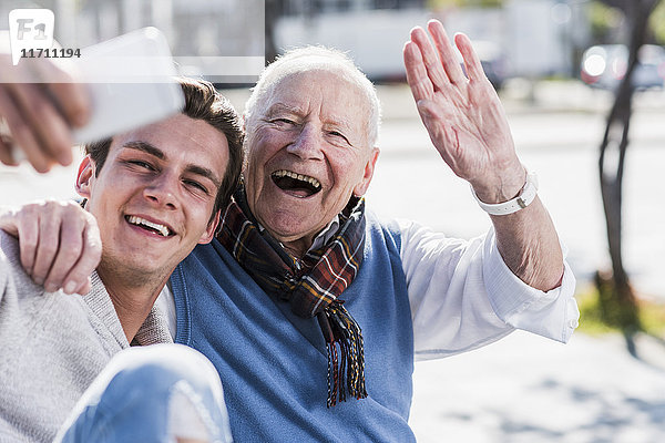 Glücklicher älterer Mann und erwachsener Enkel  der einen Selfie nimmt.