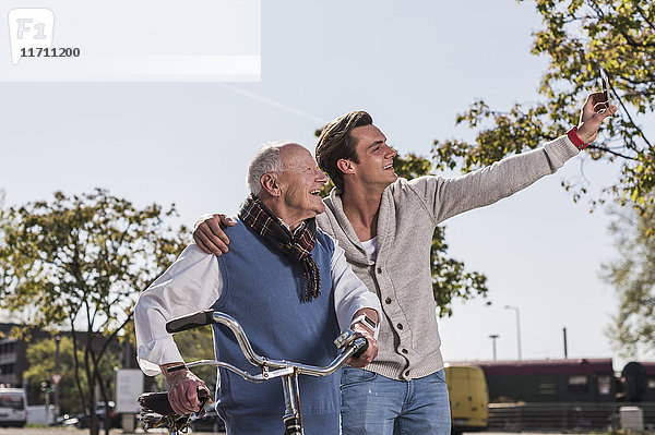 Senior Mann und erwachsener Enkel mit einem Selfie im Freien