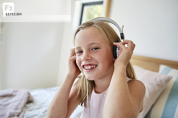 Porträt eines lächelnden kleinen Mädchens  das zu Hause Musik mit Kopfhörern hört.