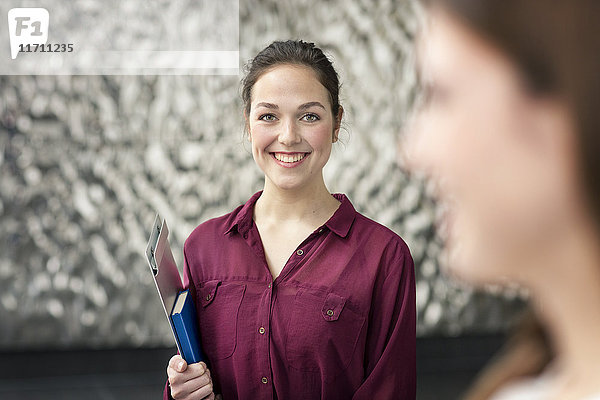 Porträt einer lächelnden jungen Geschäftsfrau mit Notizbuch und Klemmbrett