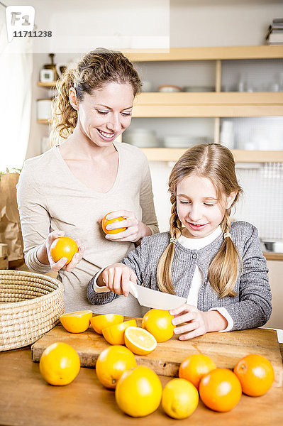 Mutter und Tochter schneiden Orangen in der Küche