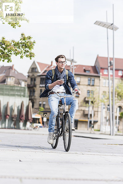 Junger Mann mit Fahrrad in der Stadt halten Handy
