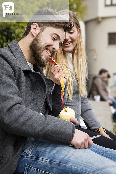 Junge Frau füttert ihren Freund mit einer Apfelschale.